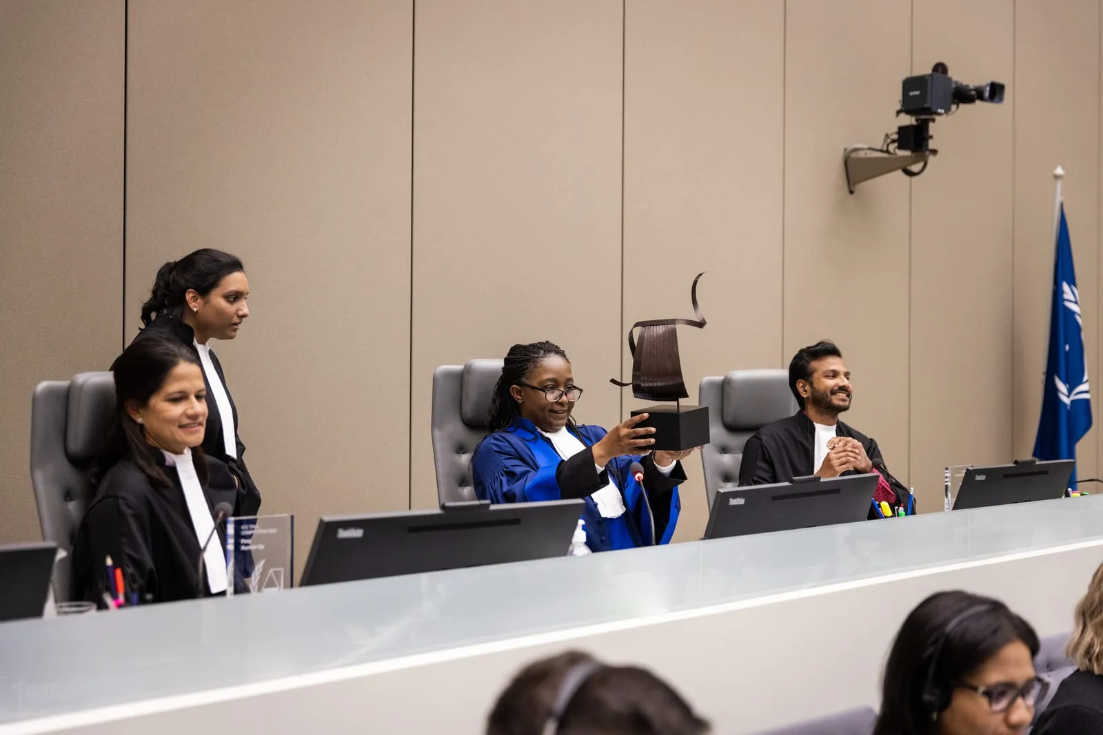 Farhaan Ahmed on the judging bench at the Final of the 2022 English edition of the ICC Moot Court Competition, a fellow judge holding up the winner's trophy