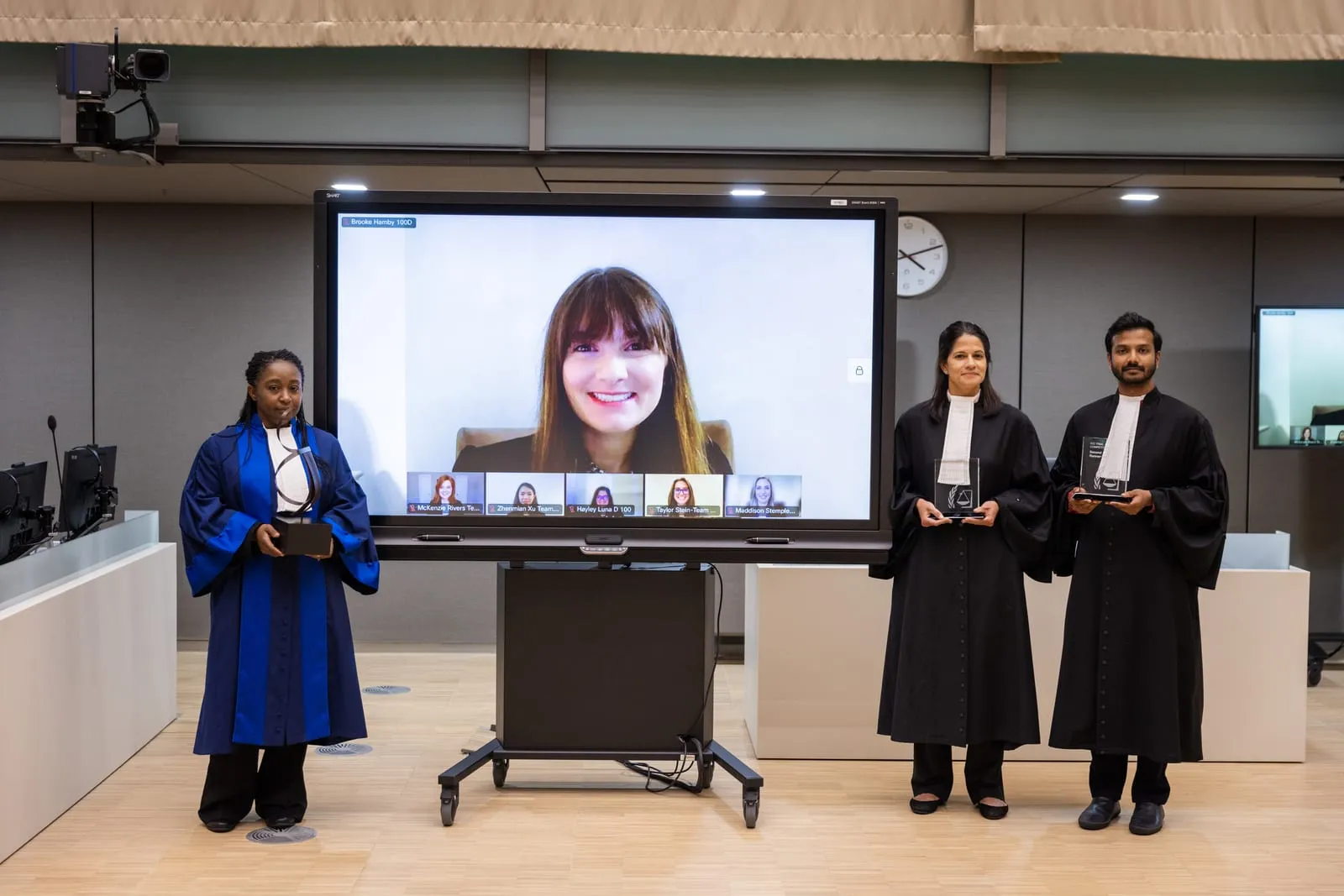 Farhaan Ahmed and fellow judges holding the trophies at the hybrid Final of the 2022 ICC Moot Court Competition, a finalist joining on screen