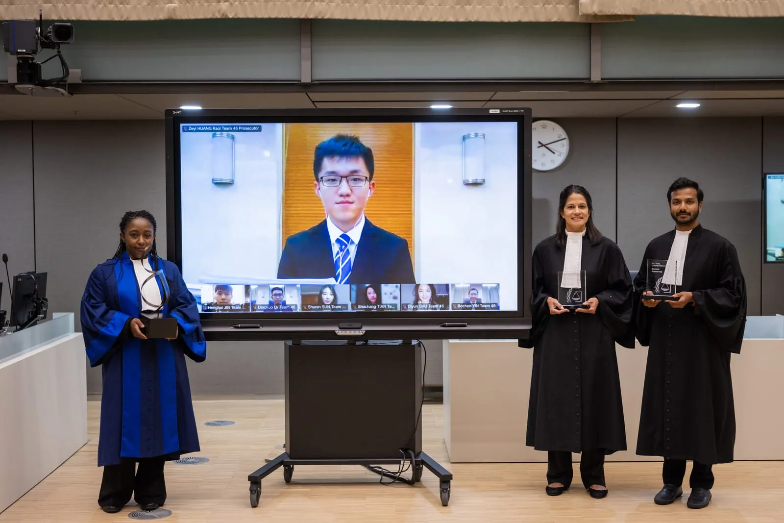 Farhaan Ahmed and fellow judges with the awards beside a screen of remotely-connected finalists at the 2022 ICC Moot Court Competition Final