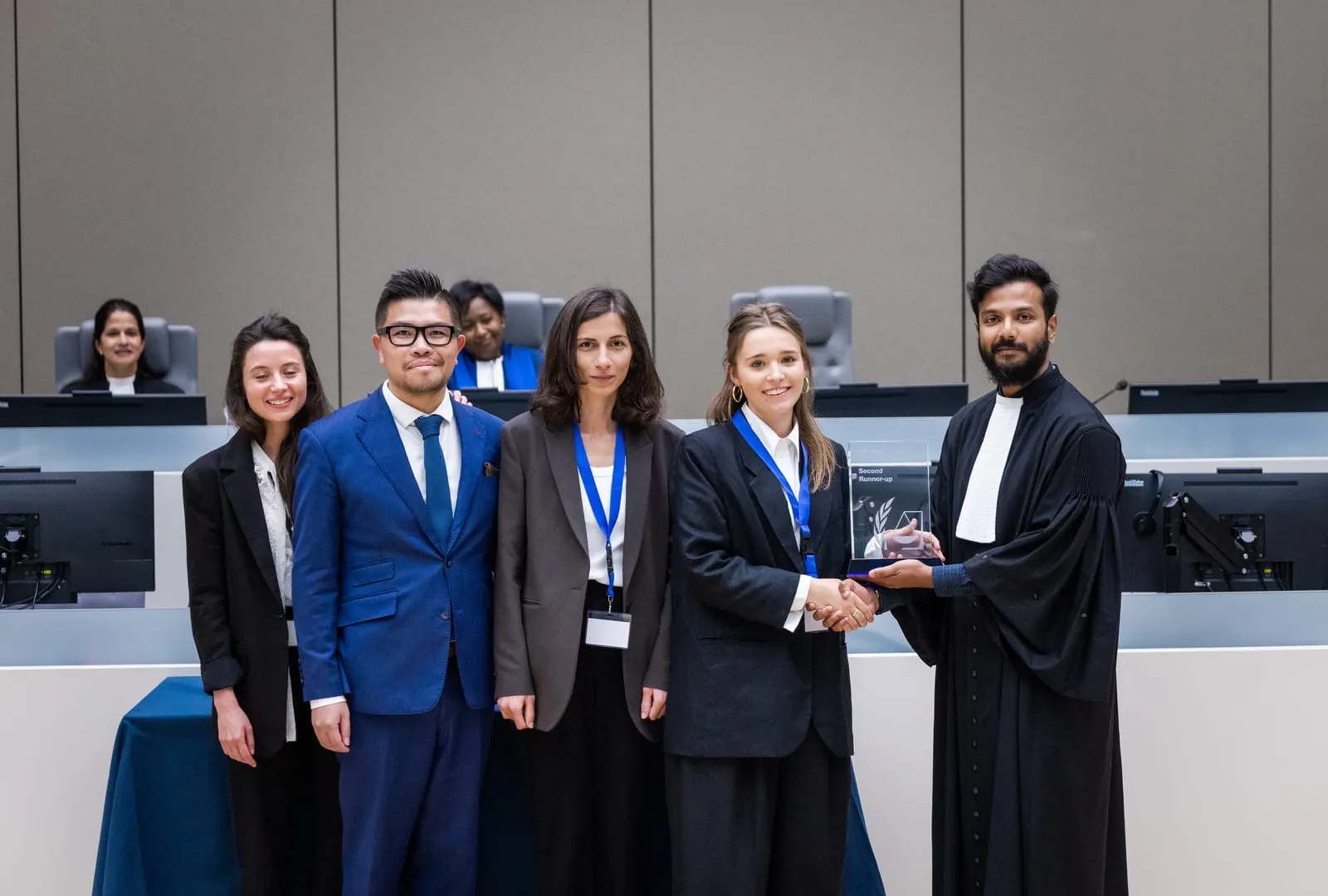 Farhaan Ahmed, in advocate's robes, presenting the second runner-up award to a team in the ICC courtroom at the Final of the 2023 English edition of the ICC Moot Court Competition