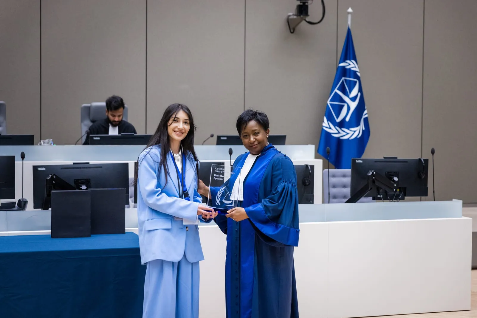 A competitor receiving the Best Overall Speaker award from a judge in the ICC courtroom at the 2023 ICC Moot Court Competition Final